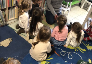 Dzieci słuchają książki czytanej przez Panią Bibliotekarkę