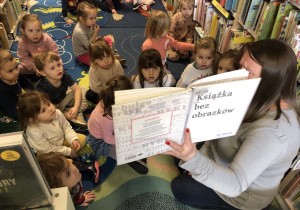 Dzieci słuchają książki czytanej przez Panią Bibliotekarkę