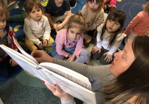 Dzieci słuchają książki czytanej przez Panią Bibliotekarkę