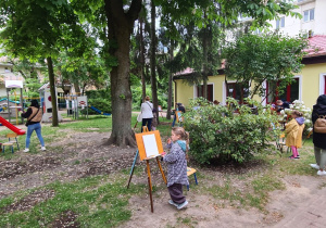 Dzieci malują na sztalugach w ogrodzie
