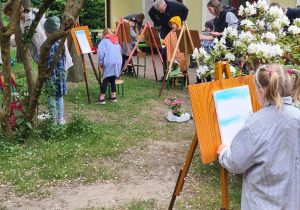 Dziecko maluje na sztaludze w ogrodzie