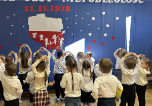 Dzieci pokazują serce z dłoni na tle dekoracji