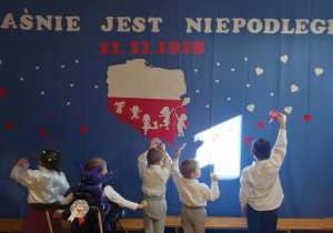 Dzieci pokazują kotyliony na tle dekoracji