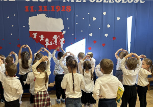 Dzieci pokazują serce z dłoni na tle dekoracji