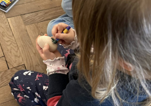 Dzieci ozdabiają drewniane jajka pastelami