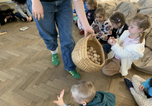 Pani rozdaje drewniane jajka do ozdobienia