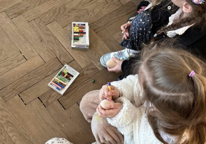 Dzieci ozdabiają drewniane jajka pastelami